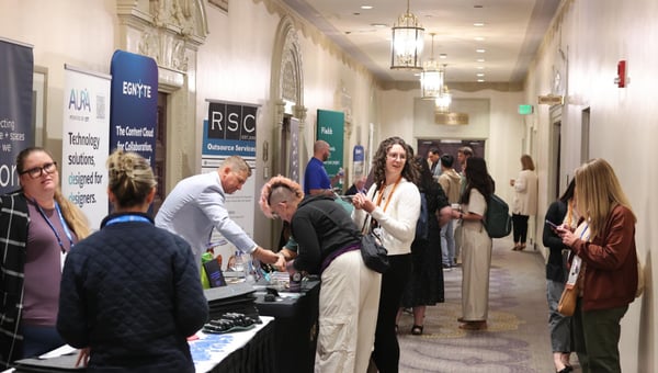 Attendees visiting sponsor tables lining a hotel hallway