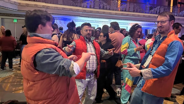 Attendees in matching orange puffer vests posing together on the dance floor