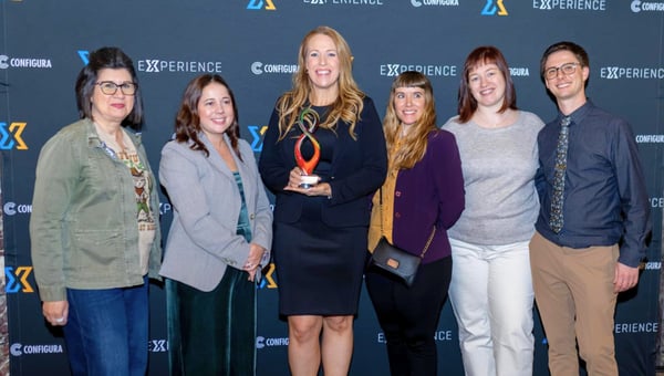A winning team posing with their glass Configura Award in front of the Experience backdrop