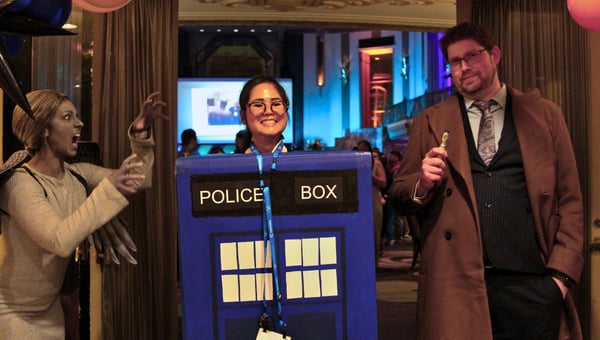 An attendee in a blue police box costume posing with guests in period outfits