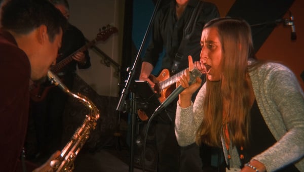 An attendee singing with the live band as a saxophonist plays beside her